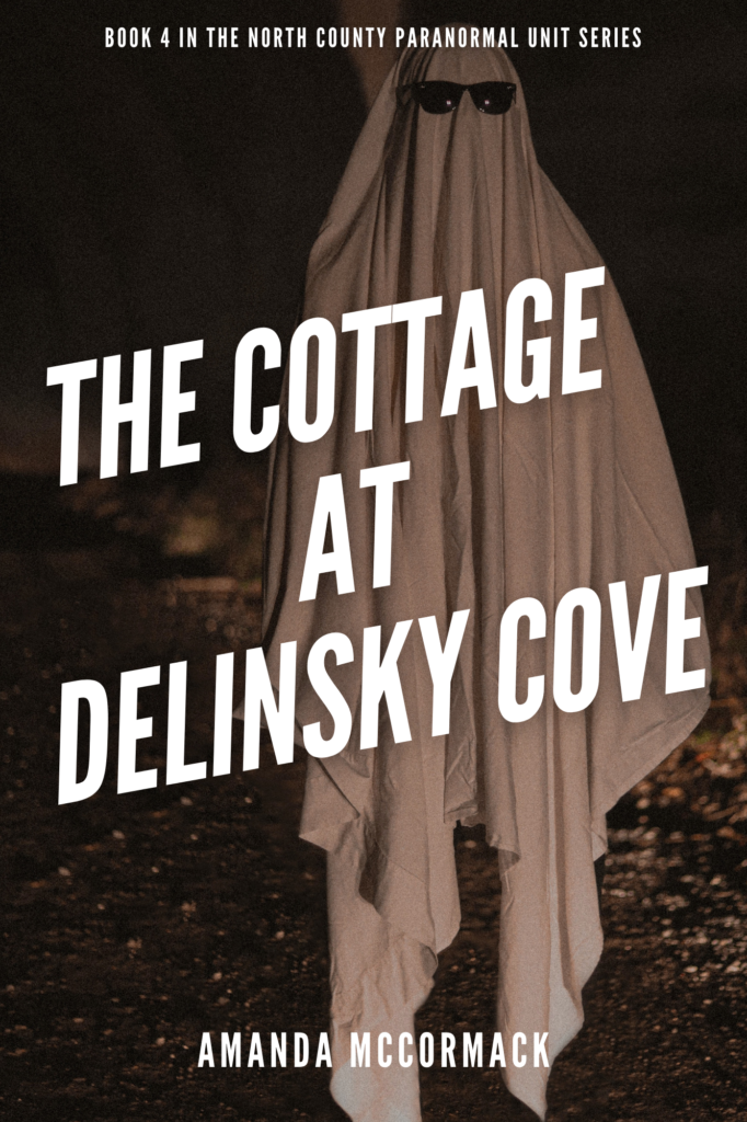 A person in a ghost costume, complete with sunglasses, stands in the foreground. Behind them is a little bit of gravel road, but it is very dark. The ghost is lit with dim, dirty light. Text over it reads The Cottage At Delinsky Cove